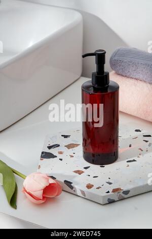 Un plateau en marbre en forme d'hexagone avec une bouteille de pompe à étiquette vide placée sur, décorée d'une fleur rose. Emballage de conteneur pour marque de soins de la peau Banque D'Images