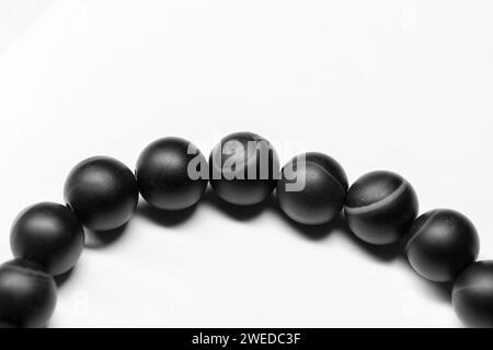 Bracelet en perles rondes en agate noire repose sur fond blanc, photo gros plan avec mise au point sélective Banque D'Images