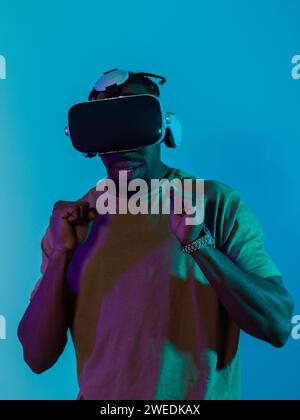 Homme afro-américain se plonge dans une expérience de jeu d'horreur palpitante en utilisant des lunettes VR, créant une atmosphère isolée et intense contre un Banque D'Images