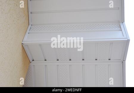 Gros plan d'un soffite blanc en uPVC, installé le long de la ligne de toit de la maison. Panneau de soffite en plastique sous la planche de bord du toit. Banque D'Images