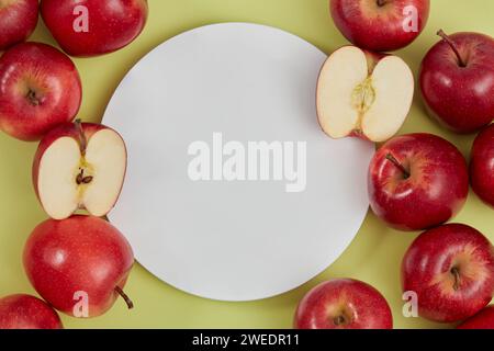 Piédestal pour les maquettes de produits cosmétiques et d'emballage présentent une présentation et beaucoup de pommes rouges mûres décorées sur fond vert. Podiu blanc rond Banque D'Images