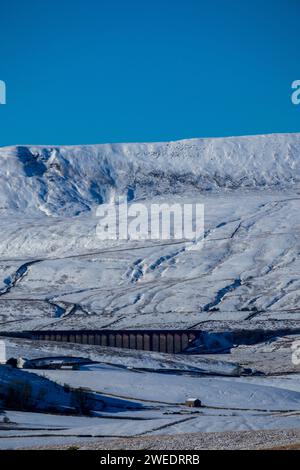 Une vue lointaine du Viaduc Ribblehead sous Whernside par une belle journée d'hiver dans les Yorkshire Dales en Angleterre, avec beaucoup de neige sur le sol. Banque D'Images