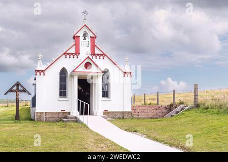 Petite chapelle catholique ornée attraction touristique sur les îles Orcades en Écosse avec une pelouse tondue à l'avant et une croix avec Jésus sur le côté Banque D'Images