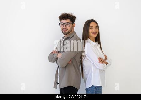 Couple dans les complets debout dos à dos avec les bras croisés sur fond blanc Banque D'Images