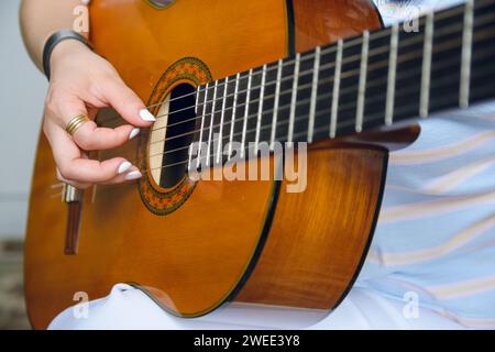 Gros plan d'une jeune femme caucasienne méconnaissable jouant de la guitare acoustique, se concentrer sur la main sur les cordes au trou de son de la guitare acoustique, espace de copie. Banque D'Images