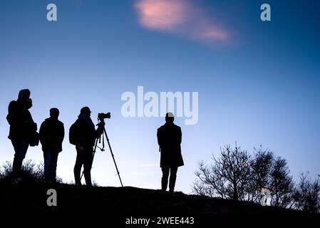 Silhouette d'un groupe de personnes regardant le coucher du soleil sur une colline Banque D'Images