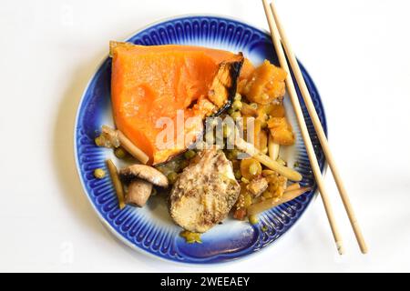 Un morceau de poisson frit avec des légumes cuits sur une assiette. Banque D'Images