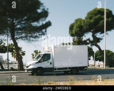 Mallorca, Espagne - 27 juin 2023 : un semi-camion réfrigéré blanc Iveco descend Av. De Gabriel Roca, capturé avec un objectif tilt-shift, révélant le port de la marina en arrière-plan. Banque D'Images