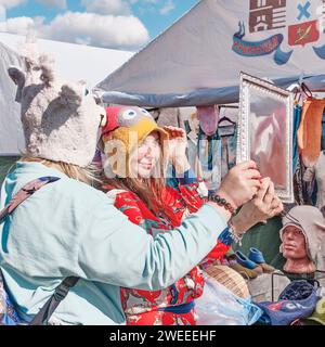 Deux jeunes femmes essayant des chapeaux de laine feutrés créatifs drôles à la foire traditionnelle d'Irbit, en Russie Banque D'Images