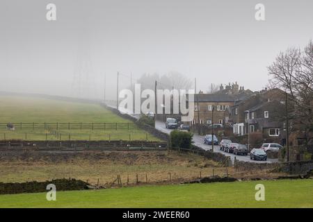 La brume sur une colline de Pennine près de Queensbury transforme les fermes et les marcheurs en silhouettes fantômes alors que le temps hivernal saisonnier de janvier se rapproche. Banque D'Images