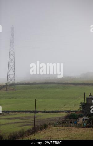 La brume sur une colline de Pennine près de Queensbury transforme les fermes et les marcheurs en silhouettes fantômes alors que le temps hivernal saisonnier de janvier se rapproche. Banque D'Images