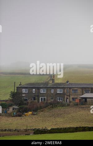 La brume sur une colline de Pennine près de Queensbury transforme les fermes et les marcheurs en silhouettes fantômes alors que le temps hivernal saisonnier de janvier se rapproche. Banque D'Images