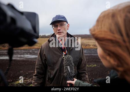 Le Dr Alastair Ruffell de Queens University Belfast s'adressant aux médias près du site de Bellaghy, Co Londonderry, où des restes humains de carbone datés de 2 000 à 2 500 ans ont été trouvés. Un anthropologue médico-légal certifié a déterminé que les restes antiques sont probablement un homme âgé entre 13-17 ans au moment de la mort. L'unité archéologique de l'équipe de récupération du corps du PSNI a fait la découverte lors de fouilles, après avoir été alertée de la présence d'os humains à la surface de tourbières à Bellaghy en octobre 2023. Date de la photo : jeudi 25 janvier 2024. Banque D'Images