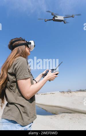 jeune femme volant un drone avec télécommande et lunettes de réalité virtuelle Banque D'Images