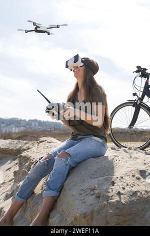 jeune femme volant un drone avec télécommande et lunettes de réalité virtuelle Banque D'Images