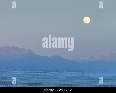 HAMI, CHINE - 25 JANVIER 2024 - Une lune brillante se lève au-dessus des montagnes de Tianshan est à Hami, province du Xinjiang, Chine, 25 janvier 2024. Le premier plein Banque D'Images