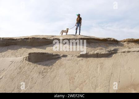 jeune femme marchant avec son chien sur le sable dans le désert Banque D'Images