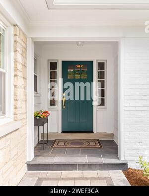 Un détail d'une porte d'entrée sur la maison avec la pierre et le parement de briques blanches, trottoir en pierre, et une porte d'entrée bleue - verte colorée. Banque D'Images