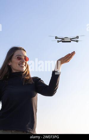 petit drone atterrissant sur la paume de la jeune femme Banque D'Images