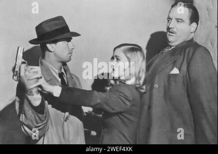 Alan Ladd et Veronica Lake jouent dans This Gun for Hire (1942), un film noir captivant. Ladd dépeint Philip Raven, un tueur à gages qualifié, tandis que Lake joue Ellen Graham, une chanteuse de boîte de nuit et agent secret. L'intrigue se déroule alors que Raven s'emmêle dans un dangereux complot d'espionnage impliquant Graham, conduisant à des rebondissements. Banque D'Images