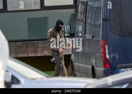 Montabaur, Allemagne. 25 janvier 2024. Un officier SEK regarde son smartphone après l'attaque. Selon la police, trois personnes, dont un enfant, ont été tuées dans un acte de violence dans un quartier résidentiel. Les services d’urgence ont découvert que l’auteur présumé avait été grièvement blessé après être entré dans le bâtiment, selon un porte-parole de la police. Crédit : Sascha Ditscher/dpa/Alamy Live News Banque D'Images