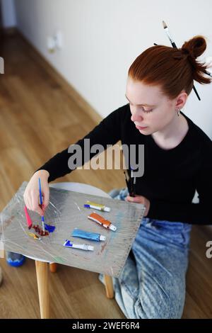 adolescente mélangeant des peintures acryliques Banque D'Images