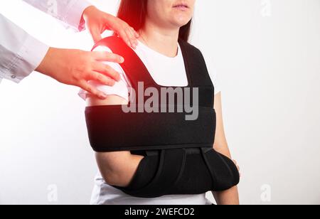 Un médecin orthopédiste examine une patiente fillette après une blessure à l'épaule. Bandage sur l'articulation de l'épaule après luxation de l'épaule et fracture osseuse. Banque D'Images