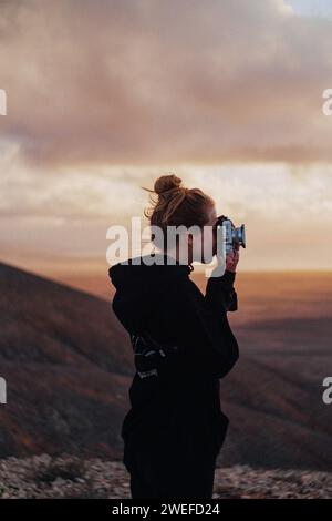 Photographe femme prenant des photos pendant un coucher de soleil Banque D'Images