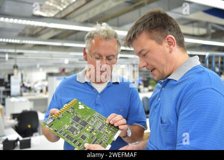travailler dans une usine de fabrication de microélectronique - assemblage de composants et soudure - groupe de travailleurs au travail d'équipe Banque D'Images