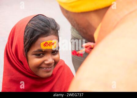 Les enfants se font peindre le nom de Lord RAM sur leur front, à la veille de la cérémonie de consécration du temple RAM, à Ayodhya, Uttar Pradesh, Inde, le 22 janvier 2024. Banque D'Images