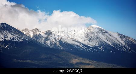 fond de nature de la puissante crête haute tatra au printemps à midi. sommets rocheux enneigés de slovaquie sous un ciel nuageux Banque D'Images