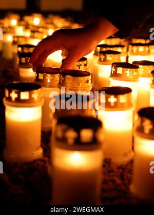 Brokstedt, Allemagne. 25 janvier 2024. Une personne place une bougie parmi d'autres bougies allumées sur le parvis de l'église protestante pendant le service commémoratif pour marquer l'anniversaire de l'attaque au couteau contre un train régional à Brokstedt. Un an après le jour de l'attaque au couteau contre un train régional entre Kiel et Hambourg, au cours de laquelle deux personnes ont été tuées et d'autres blessées, les victimes sont rappelées. Crédit : Christian Charisius/dpa/Alamy Live News Banque D'Images