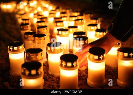 Brokstedt, Allemagne. 25 janvier 2024. Une personne place une bougie parmi d'autres bougies allumées sur le parvis de l'église protestante pendant le service commémoratif pour marquer l'anniversaire de l'attaque au couteau contre un train régional à Brokstedt. Un an après le jour de l'attaque au couteau contre un train régional entre Kiel et Hambourg, au cours de laquelle deux personnes ont été tuées et d'autres blessées, les victimes sont rappelées. Crédit : Christian Charisius/dpa/Alamy Live News Banque D'Images