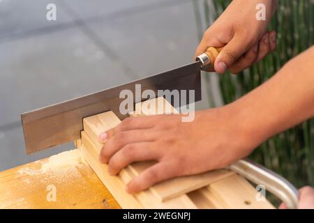 Un homme sciant des lattes de bois dans un atelier de menuiserie Banque D'Images