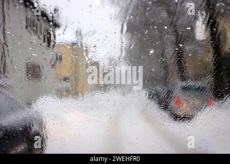 Vue floue à travers le pare-brise mouillé d'une voiture en hiver pendant les chutes de neige Banque D'Images