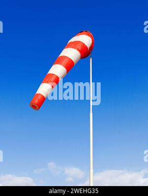 une chaussette rouge et blanche souffle dans une légère brise contre un ciel bleu Banque D'Images