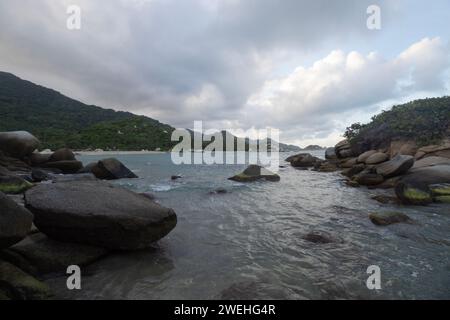 Grands rochers dans la mer des caraïbes avec un crépuscule bleu nuageux sur la plage d'arrecife au parc national tayrona Banque D'Images