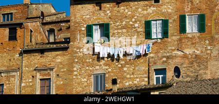 Une femme accroche le linge sur la façade d'une grande maison à Montepulciano, Toscane, Italie, Europe Banque D'Images