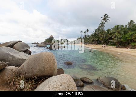 Célèbre plage nationale colombienne tayrona connue sous le nom de Cabo San Juan avec touriste dans la mer des caraïbes et point de vue roustique cabane au sommet d'une montagne Banque D'Images