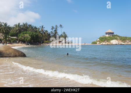 femme nageant dans la mer turquoise des caraïbes à la plage de cabo san juan dans le parc national colombien tayrona en journée ensoleillée avec la cabane de point de vue en arrière-plan Banque D'Images