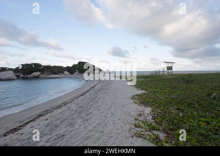 magnifique paysage de coucher de soleil sur la plage d'arrecife avec des montagnes rocheuses et une cabane de sauveteur dans le parc national colombien tayrona Banque D'Images