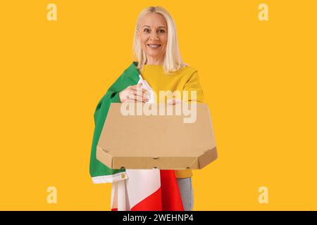 Femme mature avec drapeau de l'Italie et pizza sur fond jaune Banque D'Images