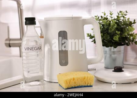 Nettoyage de la bouilloire électrique. Bouteille de vinaigre et éponge sur le comptoir dans la cuisine Banque D'Images