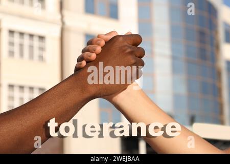 Concept de tolérance, de soutien et de coopération. Hommes de races différentes serrant les mains sur la rue de la ville, gros plan Banque D'Images