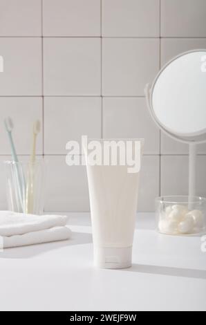 Concept de salle de bains avec serviette, brosses à dents, cocons vers à soie dans un bol transparent, miroir sur fond de mur carrelé blanc. Au milieu se trouve un tube en plastique Banque D'Images