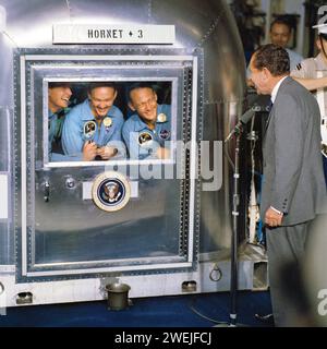 Le président américain Richard Nixon saluant les astronautes d'Apollo 11 Neil A. Armstrong, Edwin E. Aldrin et Michael Collins, à l'intérieur de l'installation de quarantaine après une mission de récupération réussie, USS Hornet, NASA, 24 juillet 1969 Banque D'Images