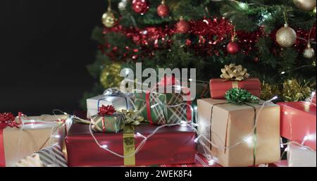 Cadeaux emballés colorés assis sous un arbre de Noël décoré Banque D'Images