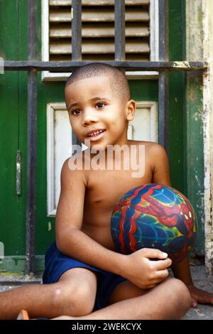 Un garçon cubain tenant son ballon de football. Vieille Havane, Cuba. Banque D'Images