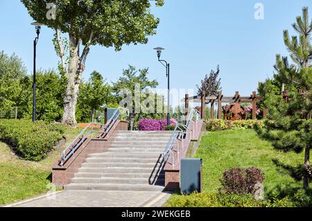 Aire de repos avec escalier entouré de fleurs fleuries et d'arbustes ornementaux à Kiev, en Europe. Place pour se reposer dans le parc de la ville Banque D'Images