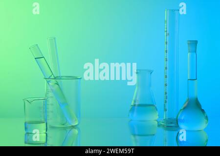 Concept de laboratoire avec verrerie de laboratoire - flacon erlenmeyer, tubes à essai et bécher rempli de liquide incolore sur fond de gradient. Espace pour affichage prod Banque D'Images